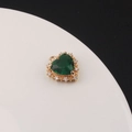 Macro detail of gold-plated heart pendant with emerald zircon and pave crystals - Green