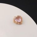 Macro detail of a gold heart pendant featuring a large pink zircon with clear stone accents - Pink