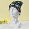Detailed view of dark green and white knitted beanie featuring fuzzy tassel textures - Green