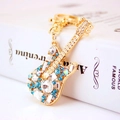 Creative gold guitar keychain with blue and white crystals on a book background - Blue