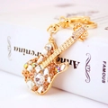 Exquisite gold guitar keychain with sparkling colorful rhinestones on a white book - Peach