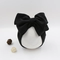 Detail of baby turban featuring a large black bow design on a white model head - Black