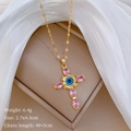 Dettaglio della collana a croce dorata con occhio blu e gemme rosa su tessuto - Collana Oro Croce (C517)