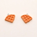Macro detail of resin waffle charms with realistic texture and metal hanging loops - Waffle