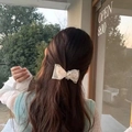 White lace bow hair clip featuring elegant rhinestones worn on long wavy brown hair - Beige Lace Bow Hair Clip