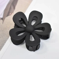 Macro detail of matte black flower hair claw clip with smooth paint finish on white background - Black