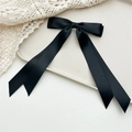Close-up of black satin double bow hair clip with long ribbons on a white tray - Black