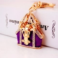 Golden and purple handbag keychain with sparkling rhinestones on minimalist book background - Purple
