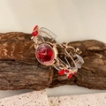 Detail einer roségoldenen Armbanduhr mit rotem Kristallzifferblatt auf Naturstein - Rot