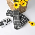 Detailed close-up of a black and white checkered linen wrist bag with a knot handle - Black Grid