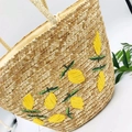 Detalle del bolso de playa de paja tejida a mano con bordado de limón amarillo y hojas verdes - Color Natural