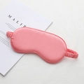 Pink faux silk sleep mask with elastic strap shown on a magazine for travel and nap - Watermelon red