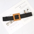 Detail of black woven belt featuring a square wooden buckle on a minimalist magazine background - Big Square Buckle Black