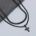Detail of a black layered cuban chain necklace with a cross pendant on a stone surface - Black