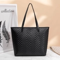 Detail showing wave-patterned quilting on black tote bag with slender shoulder straps - Black