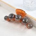 Détail d'une pince à cheveux ambre avec perles marbrées sur un plateau en velours - Marbre Sphérique / Pince à Cheveux Planète Dégradé Café