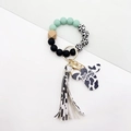 Macro detail of cow print tassel and Mama cow head tag on a western style keychain - Emerald Green