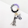 Close-up of Mama pendant with purple and black beads, cow print tassel on wristlet keychain - Purple