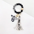 Detail of Western style cow print keychain with Mama bull head charm and leather tassel - Black