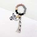 Detail of cow print wristlet keychain with Mama wooden bull head and tassel accent - Caramel color