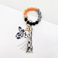 Detail of cow print keychain bracelet with Mama bull head pendant and fringe tassel - Orange