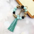 Detailed close-up of leopard print silicone beads and light blue leather tassel keychain - Green