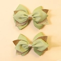 Detailed close-up of green and gold glitter bow hair clips for kids on beige background - Grass Green