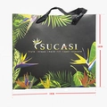 Detail of tropical palm leaf gift bag with gold branding and black braided handles - Tropical Plant Black Tote Bag