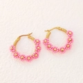 Detalle de pendientes de aro hechos a mano con flores de cuentas rosas y hilo dorado - Rosa