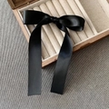 Detalle de la pinza para el pelo con lazo de satén negro sobre una caja de madera - Pinzas de pelo pico de pato / Corto/Pieza / Negro
