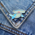 Close-up of blue and green enamel hammerhead shark brooch pin on denim fabric - Hammerhead Shark