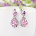 Roze druppelvormige zirkonia oorbellen met zilver aan een witte keramische beker - Oorbelpinnen / Roze