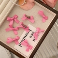 Dettaglio di fermagli per capelli con fiocchi rosa e base in metallo su vassoio di perle - rosa acceso