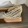 Detalle de diadema de lino tejida a mano en beige con textura de malla y puntas negras - C Cuadrado Rejilla Calada