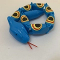 Articulated blue plastic toy snake with colorful eye patterns and red tongue - Blue