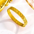 Makro-Detail des goldenen Titanstahl-Armreifs mit feinem gestepptem Kreuzmuster-Design - Gesteppt Gewebt / Gold
