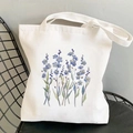 White canvas tote bag with blue floral watercolor painting on a stylish metal chair - Blue Forget-me-not