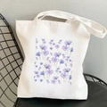 White canvas tote bag featuring purple and blue cosmos floral print on a black chair - Blue and Purple Cosmos