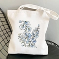 White canvas tote bag featuring blue watercolor cosmos flowers on a black chair - Blue Watercolor Flowers