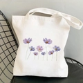 White canvas tote bag featuring purple floral illustration on a black metal chair - Purple Flower Illustration