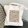 White canvas tote bag featuring a pink cosmos floral print on a minimalist black iron chair - Rectangle Pink Floral