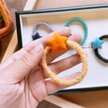 Gros plan sur un élastique à cheveux en peluche jaune avec étoile orange pour enfants - Étoile Orange