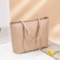Détail du sac cabas matelassé beige avec surpiqûres en V sur surface marbre - Kaki