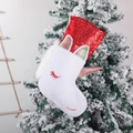 Calza di Natale unicorno bianco con paillettes rosse appesa a un albero innevato - Rosso