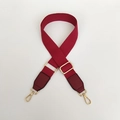Close-up of deep red canvas shoulder strap with golden metal buckles and leather ends - Burgundy / Silver