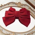 Pinza de lazo rojo de tres capas con textura granulada sobre un espejo vintage - Rojo
