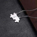 Macro shot of silver puzzle piece pendants on black leather texture background - O Chain / Silver