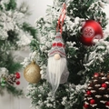 Detail view of a gray knit Christmas gnome ornament hanging on a snowy festive tree branch - Style C