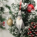 Gnomo di Natale grigio in maglia appeso a un albero innevato con palline festive - Stile B