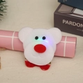 Close-up of a glowing plush bear Christmas brooch with LED eyes and a red nose - Glowing Bear Style